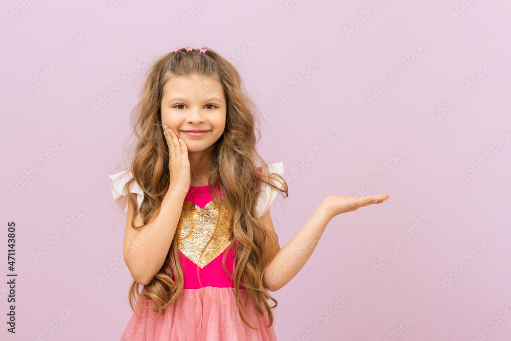 The little princess points to the advertisement. A child with curly hair. Purple isolated background. The little princess points to the advertisement. A child with curly hair. Purple isolated background.