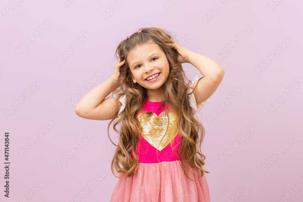 A little girl fluffs her curly hair. Isolated purple background. A little girl fluffs her curly hair. Isolated purple background.