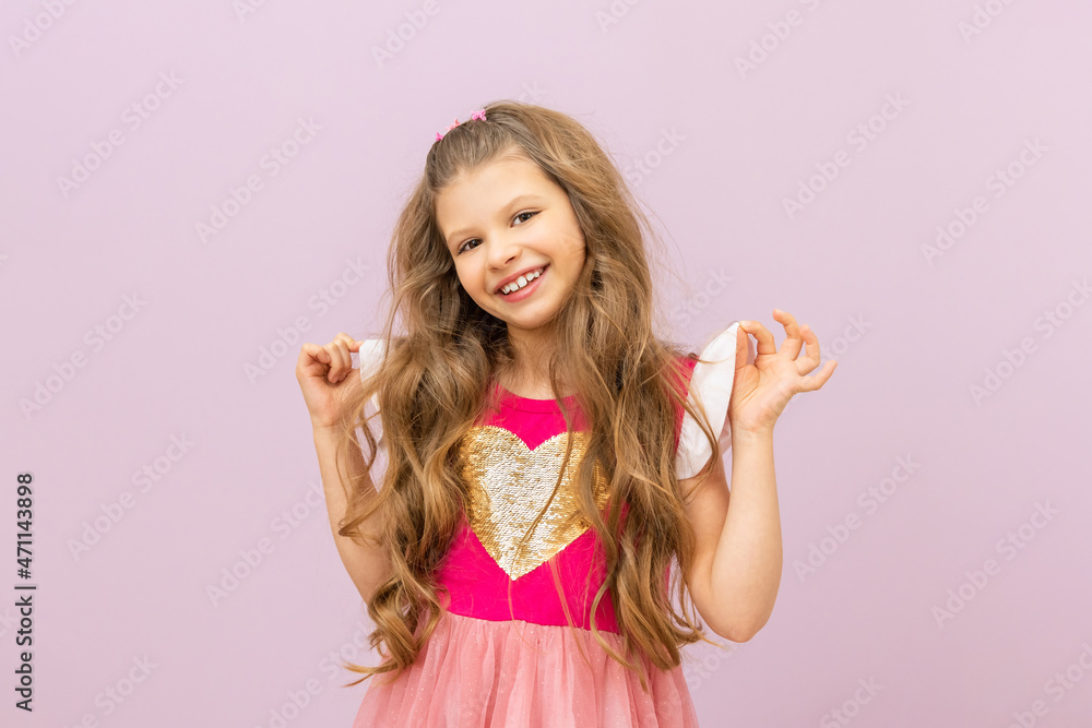 A little joyful girl flaunts an elegant dress. A child with curly hair on an isolated background. A little joyful girl flaunts an elegant dress. A child with curly hair on an isolated background.