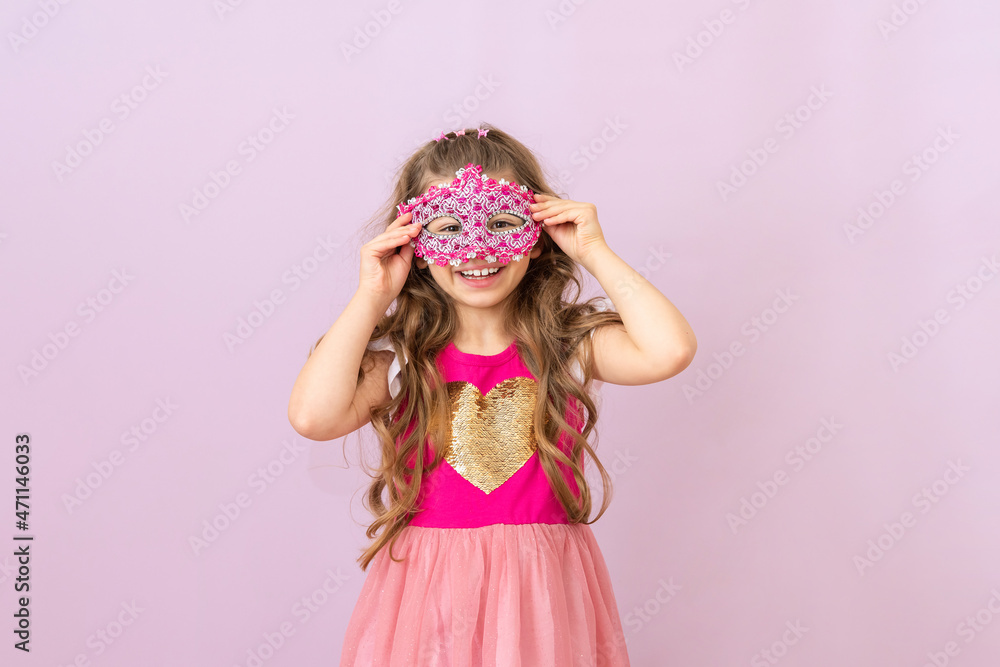 A little princess in a masquerade mask and a beautiful smile. A children with curly hair.