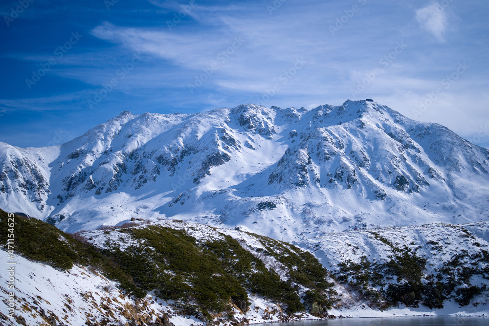 Fototapeta premium 富山県立山町にある立山の冬の雪景色のある風景 Landscape with snowy winter scenery of Tateyama in Tateyama Town, Toyama Prefecture, Japan.
