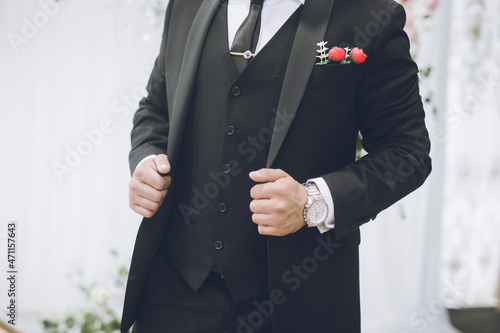 Groom's wearing classic black suit hands close up