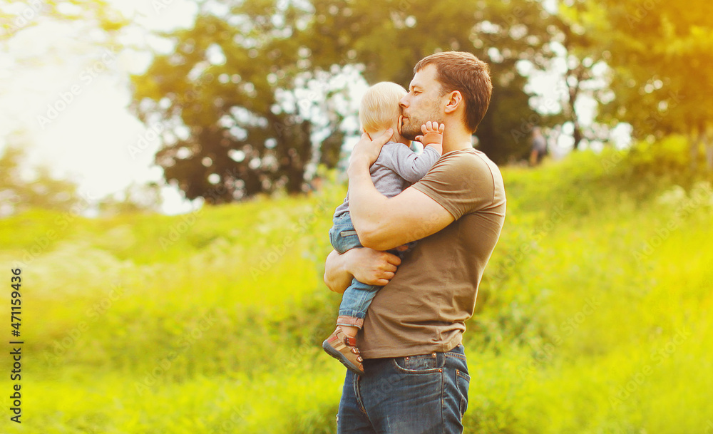 Portrait of pensive young father holding his son child looking away in summer park Portrait of pensive young father holding his son child looking away in summer park