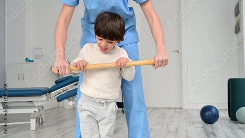 Physiotherapist and kid walking in rehabilitation center. Doctor supports a children with cerebral palsy during physiotherapy treatment. High quality 4k footage photo