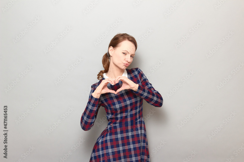 Shot of funny flirtatious young woman making heart gesture and posing