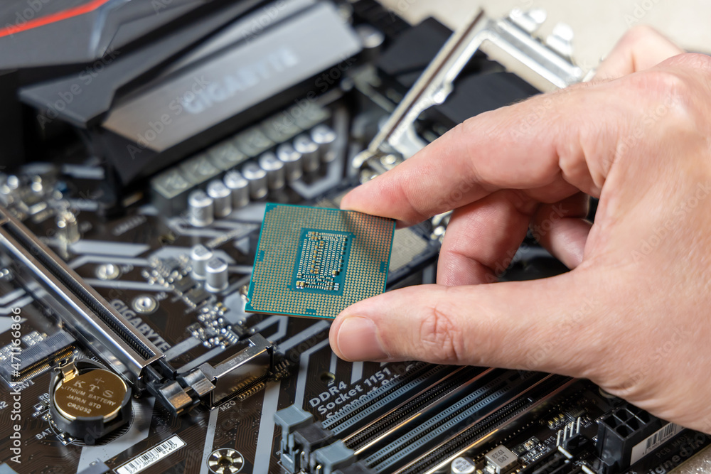 A technician holds the CPU Intel i7-9700K against the background of the  motherboard Gigabyte. Installing a CPU into socket on a motherboard. PC  assembly concept. Russia, Moscow - May 16, 2020 Stock