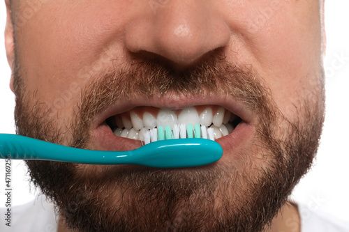 Man brushing teeth on white background  closeup. Dental care
