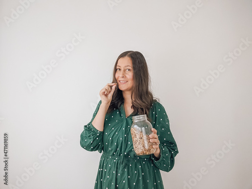 A woman in a green dress holding a jar of walnuts promoting the zero waste lifestyle and sustainable living. 