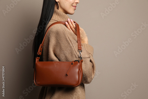 Fashionable young woman with stylish bag on beige background, closeup. Space for text