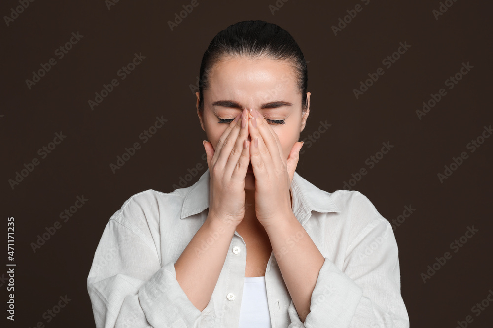 Young woman suffering from headache on dark brown background Young woman suffering from headache on dark brown background