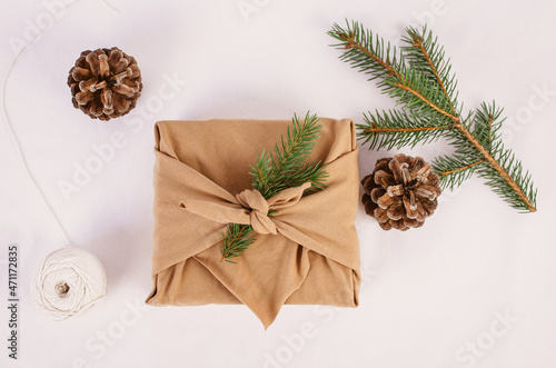 Wrapping Christmas and Holiday present with a brown zero waste Furoshiki wrap nest to winter and festive decor. 