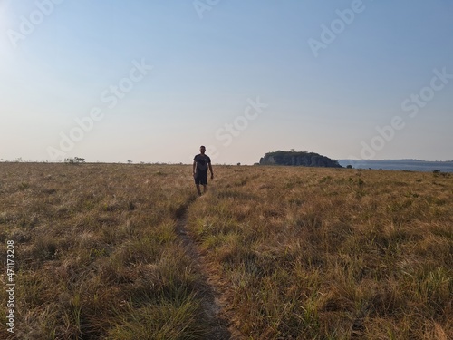Young Bolivian man hiking on a path in the middle of the grass. © robertokenapp