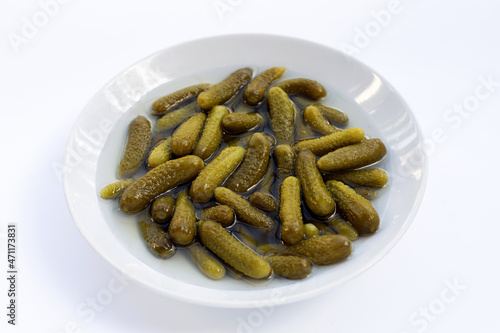 Pickled gherkins or cucumbers in bowl on white background.