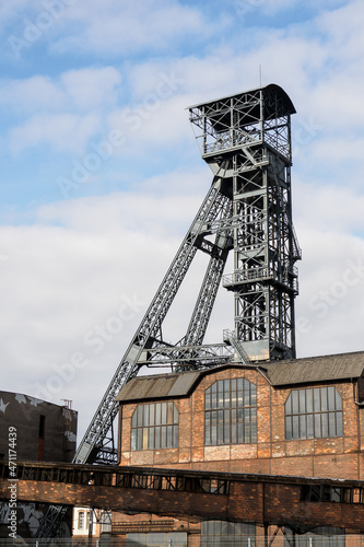 Metal mining tower with an old brick building and a corridor.