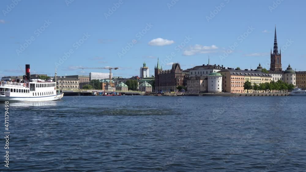 Transport boat runs between the islands on Lake Malaren in Stockholm. Riddarsholmen with towers and beautiful buildings. Famous landmarks of Sweden. Stockholm Panorama Transport boat runs between the islands on Lake Malaren in Stockholm. Riddarsholmen with towers and beautiful buildings. Famous landmarks of Sweden. Stockholm Panorama