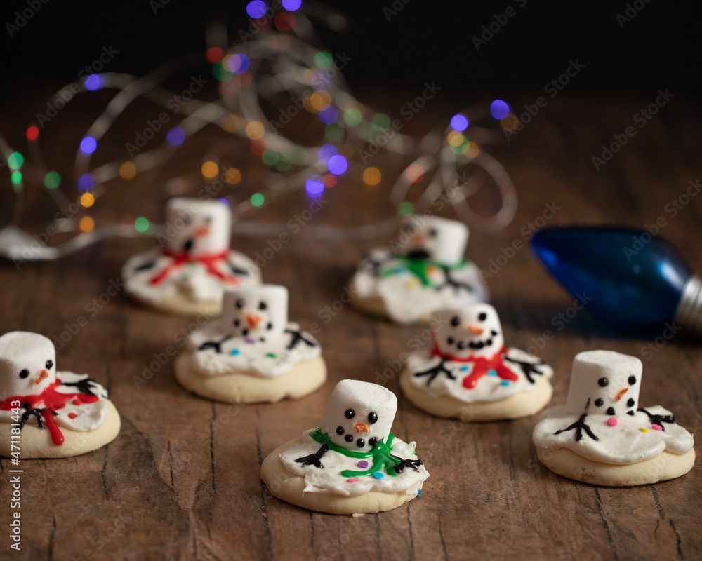 Christmas sugar cookies designed to look like melted snowman with blurred Christmas lights in the background.