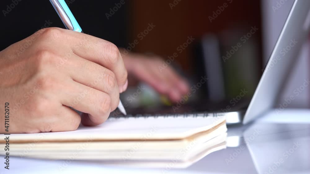 Close-up of man hands writing notes in a notebook with a pen. Businessman or entrepreneur in the home office with laptop. Online business. Close-up of man hands writing notes in a notebook with a pen. Businessman or entrepreneur in the home office with laptop. Online business.