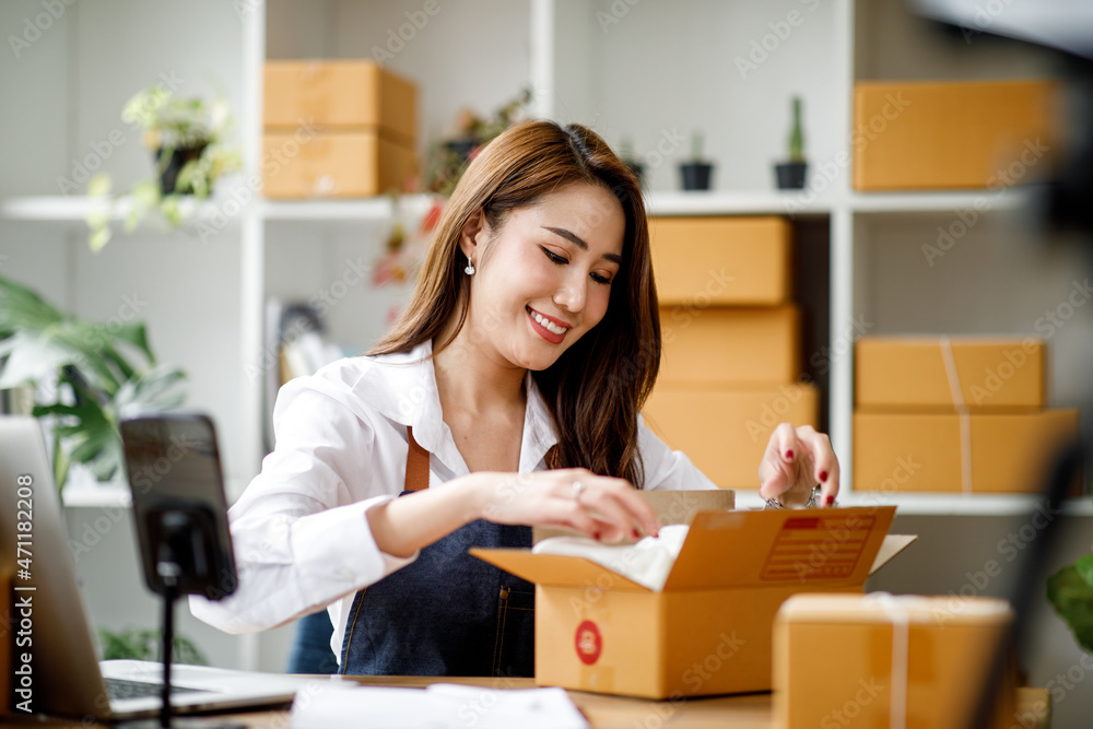 Portrait of Asian young woman SME working with a box at home the workplace.start-up small business owner, small business entrepreneur SME or freelance business online and delivery concept. Portrait of Asian young woman SME working with a box at home the workplace.start-up small business owner, small business entrepreneur SME or freelance business online and delivery concept.