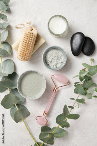 Organic cosmetic green clay, brush, massage stone and eucalyptus branch on a white textured background. The concept of spa and wellness. Top view