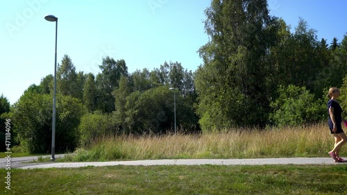 Girl and her dog wakling together on summer sunny day. Woman walks in the edge of green woods with her red dog. Red haired pet with its mistress outdoors.