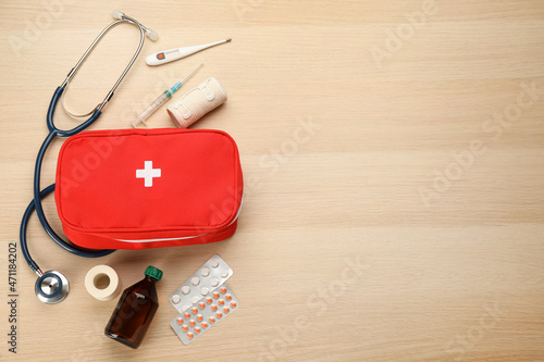 First aid kit on light wooden table, flat lay. Space for text