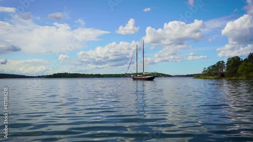 Two masts beautiful modern sailing ship moves on the sea surface on sunny summer day. Scandinavian travel. Forestly green long coastline Relax water adventure trip vacation hobby active lifestyle.