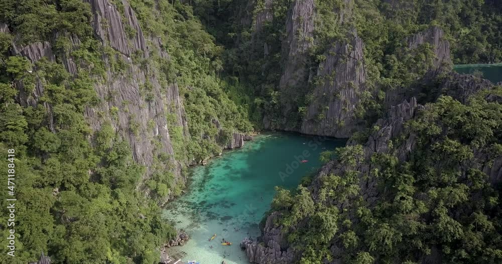 Limestone Cliffs Towering Around Crystal-clear Blue Lagoon In El Nido Island In Palawan, Philippines. drone ascend Limestone Cliffs Towering Around Crystal-clear Blue Lagoon In El Nido Island In Palawan, Philippines. drone ascend