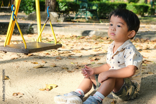 Asian boy play wooden swing in playground park