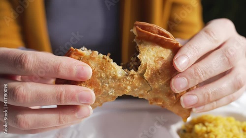 This video shows anonymous hands tearing a hot beef empanada in half, close up as it steams.