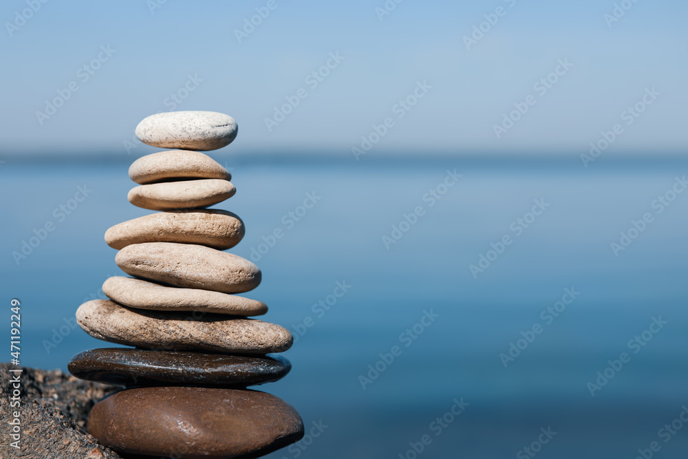 Stack of stones on rock near sea, space for text. Harmony and balance concept