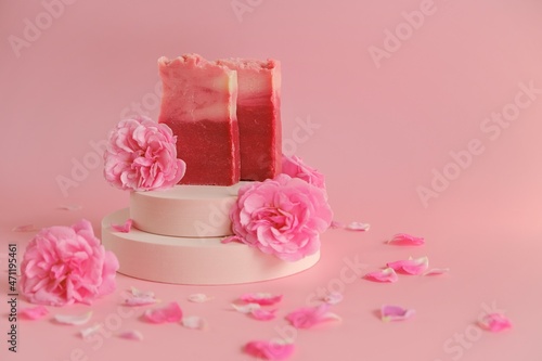 Rose soap. Beauty and aromatherapy. Flower soap. Pink soap bars and pink roses on podium on pink background.Organic Rose Soap .Organic vegan eco cosmetics.