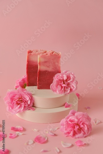 Rose soap. Beauty and aromatherapy. Flower soap. Pink soap bars and pink roses on podium on pink background. Soap with Rose extract .Organic vegan eco cosmetics.