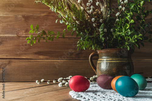 Colorful Easter eggs on wooden table. With boxwood and pussy willow branches in a vase. Rustic Easter composition on wood background. photo