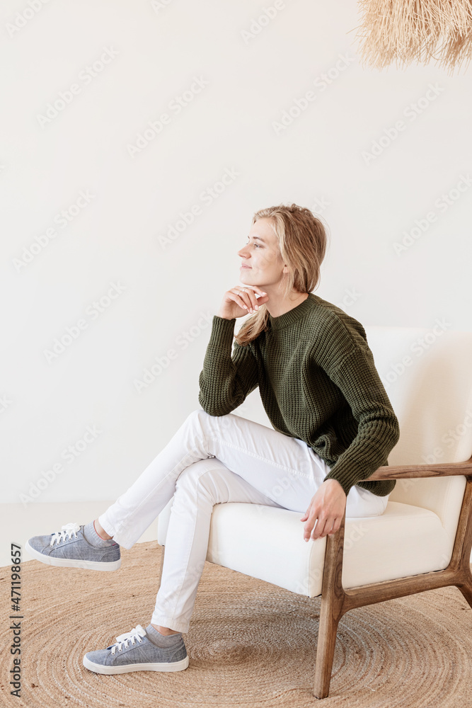 Attractive young woman sitting on the chair in light and airy interior Attractive young woman sitting on the chair in light and airy interior
