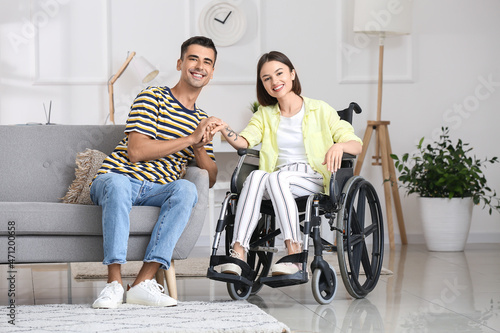 Young woman in wheelchair and her husband at home