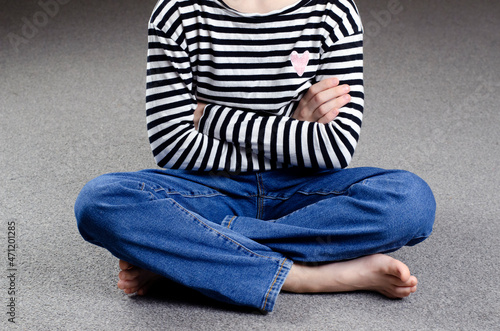 Child's bare feet. Child's legs in jeans. Sitting on the floor.