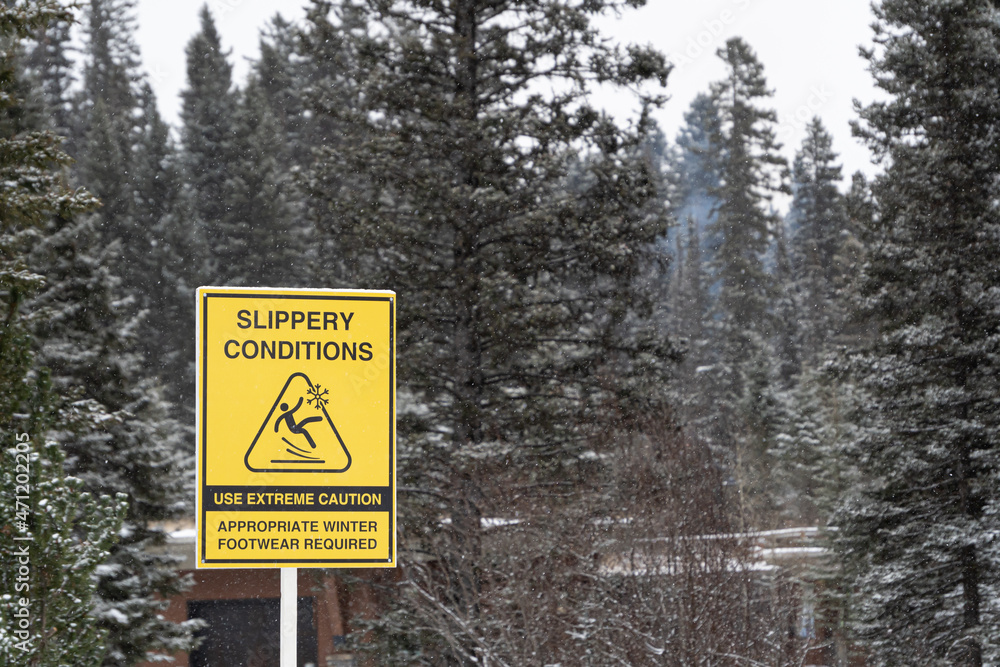Slippery conditions warning sign in national park during snowfall