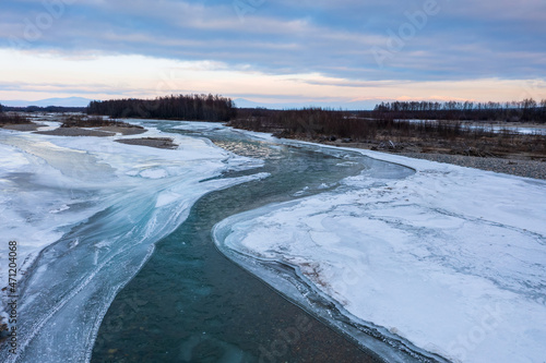 View of the freezing river. The icy banks of the river. Cold weather. Beautiful northern nature. Pure natural water. Ola River, Magadan Region, Far East of Russia. Autumn cold snap. November.
