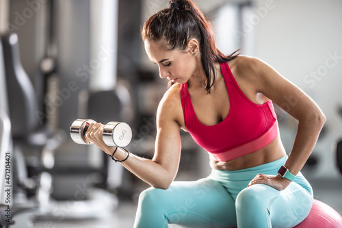 Young woman working out in the gym with dumbbells.