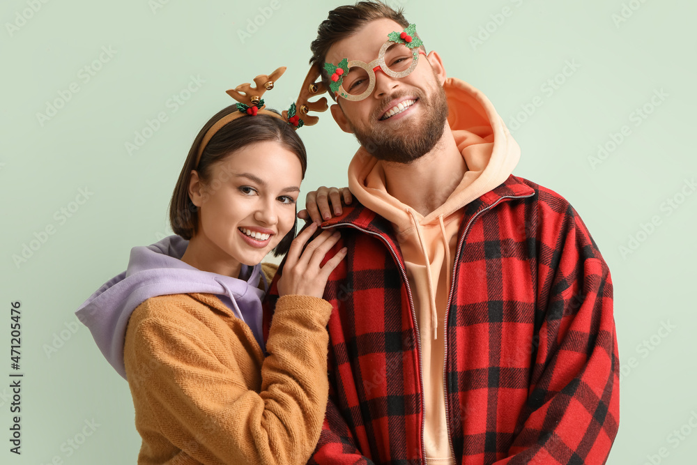 Happy young couple in stylish winter clothes and with Christmas decor on light background Happy young couple in stylish winter clothes and with Christmas decor on light background