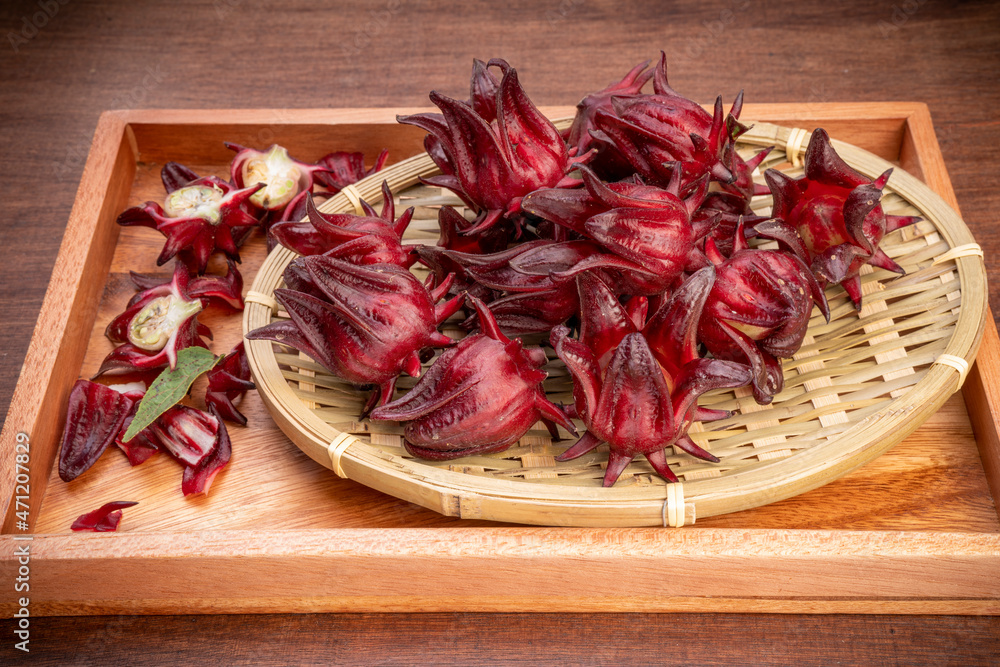 Roselle fruits in bamboo basket on wooden background, Hibiscus Sabdariffa or roselle fruits on wooden table.