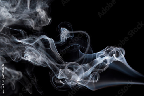 Abstract background of chaotically mixing puffs of smoke on dark background. Concept of alternative non-nicotine smoking. Color smoke on dark background. E-cigarette. Blurry image, soft focus. Vaping