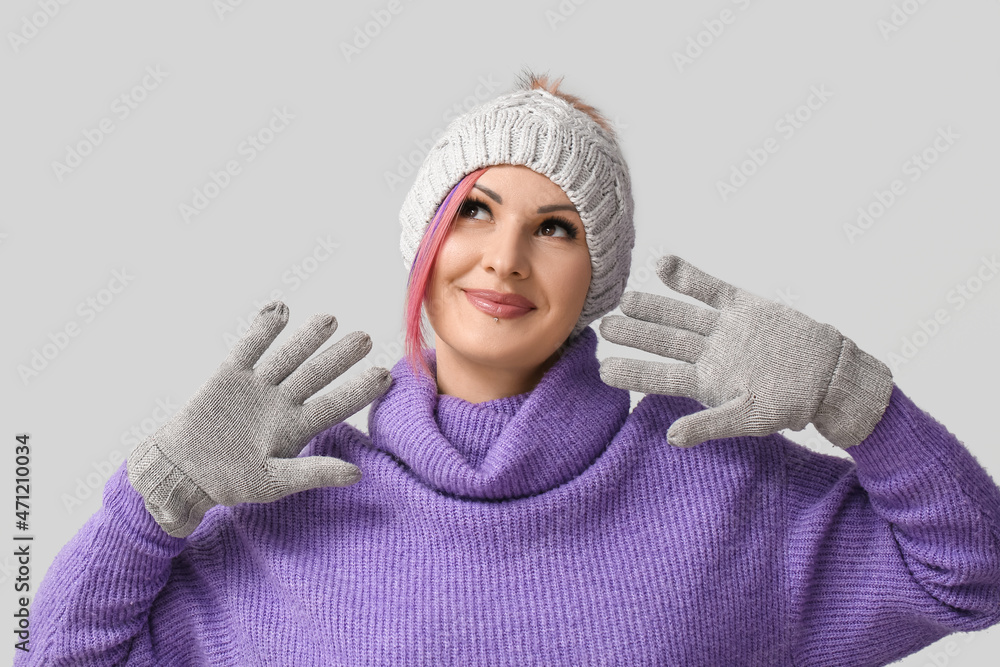 Woman in winter clothes on grey background