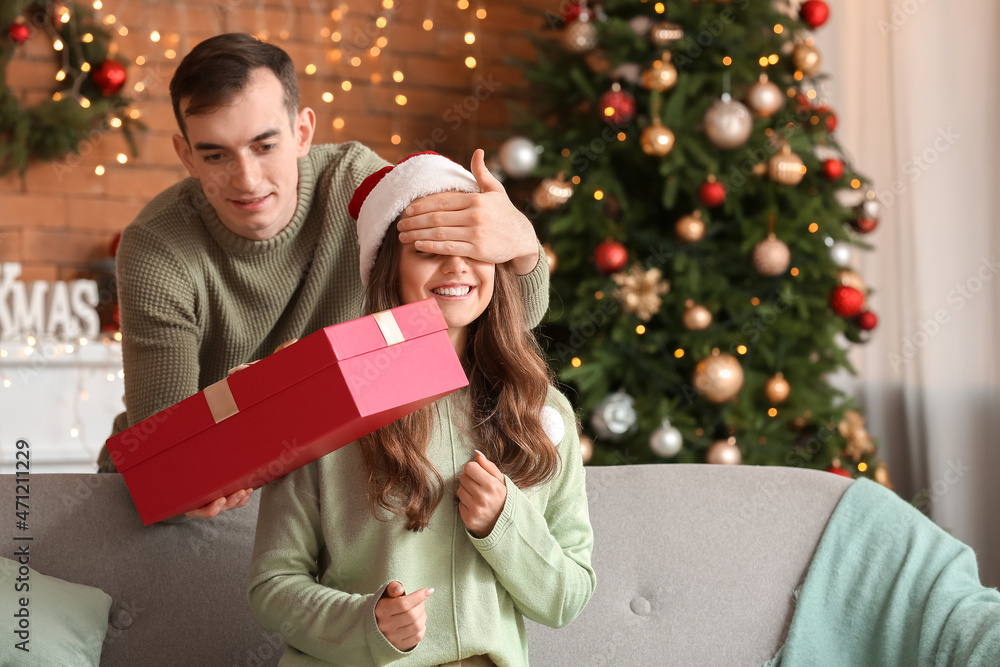 Young man greeting his girlfriend on Christmas eve at home Young man greeting his girlfriend on Christmas eve at home