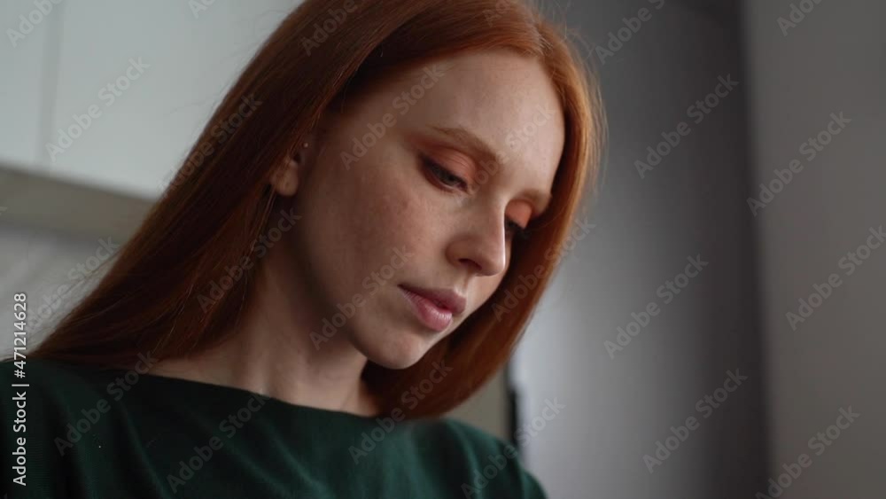 Close-up face of attractive redhead young woman with beautiful green eyes looking down, browsing online content on mobile phone. Focused lady reading book, taking notes in notebook, slow motion. Close-up face of attractive redhead young woman with beautiful green eyes looking down, browsing online content on mobile phone. Focused lady reading book, taking notes in notebook, slow motion.