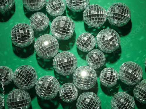 a lot of small party disco mirror balls are shining and glowing, lying on green background