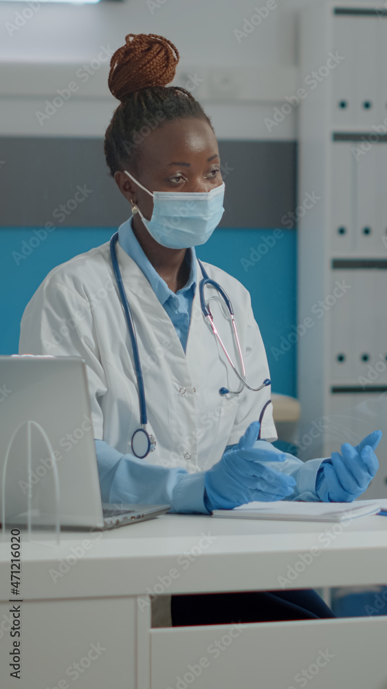 Woman working as medic chatting with old invalid man in medical cabinet at healthcare clinic. Doctor treating senior patient with disability and disease in wheelchair behind plexiglass wall Woman working as medic chatting with old invalid man in medical cabinet at healthcare clinic. Doctor treating senior patient with disability and disease in wheelchair behind plexiglass wall
