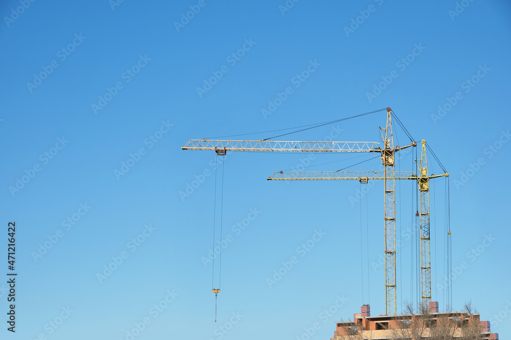High rise construction crane on background of an unfinished multi storey and multi apartment residential building.