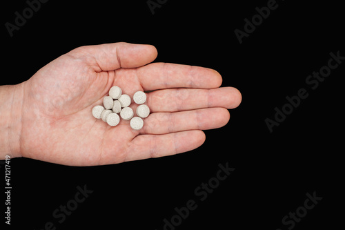 Male hand holding pills. Capsules are white. Medicines. Isolate on a black background. A remedy for diseases. Drug addiction concept. Treatment of illness with medication.