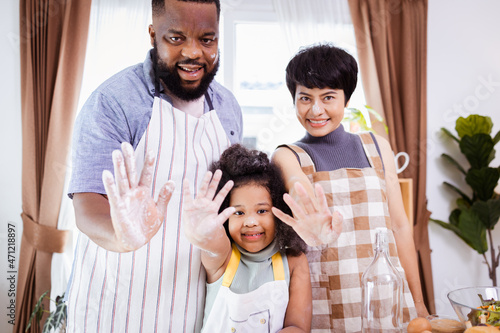 Happy African American family enjoy together while prepare the flour for making cookies at home. Look at camera.